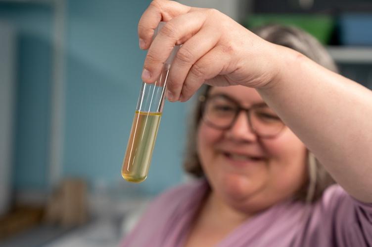 Liz Harvey holds up a tube of cultured phytoplankton that she and her study in the lab.